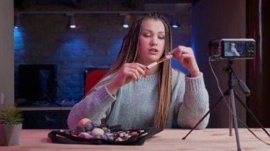 Dreadlocks canlı akışı ve neon arka plan kapalı güzellik ürünleri reklam ile genç çekici kadın blogger Closeup ateş