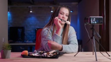 Dreadlocks canlı ve reklam kozmetik kapalı neon arka plan ile akarsu ile genç çekici kadın güzellik blogger Closeup ateş