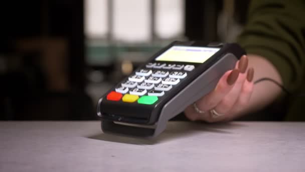 Osoba s blízkými předpoklady aplikuje kreditní kartu na terminál provádějící bezhotovostní platbu.