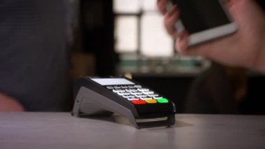 Bir fincan kahve almak başarılı temassız ödeme gerçekleştiren terminale akıllı telefon bağlar kadın yakın çekim.