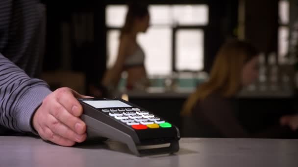 Primer plano de la mujer pasa la tarjeta de crédito a través de la máquina terminal que realiza el pago . — Vídeo de stock