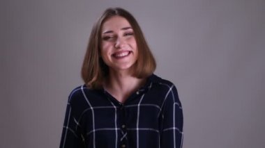 Kamera bakarak ve gri izole arka plan ile neşeyle gülümseyen genç oldukça kısa saçlı kadın Closeup ateş