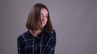 Kamera bakarak ve gri izole arka plan ile utangaçlık ile gülümseyen genç oldukça kısa saçlı kadın Closeup ateş