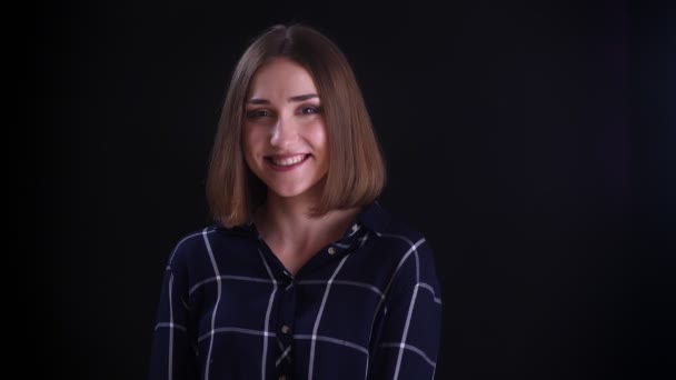 Closeup lő fiatal csinos, rövid hajú nő egyenesen a kamerát, és mosolyogva boldogan háttérrel izolált fekete — Stock videók
