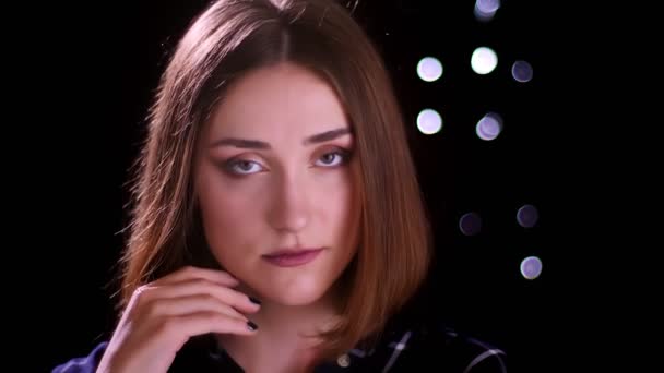 Close-up tiro de jovem muito curto cabelo fêmea posando na frente da câmera com bokeh luzes no fundo — Vídeo de Stock