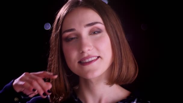 Close-up tiro de jovem muito curto cabelo feminino sorrindo alegremente olhando para a câmera com luzes bokeh no fundo — Vídeo de Stock