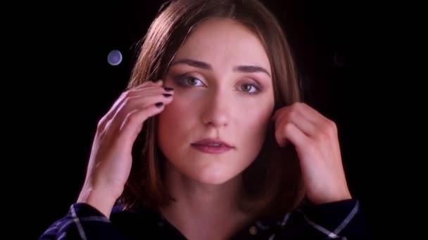 Closeup shoot of young pretty short haired female smiling seductively and looking at camera with bokeh lights on the background — Stock Video