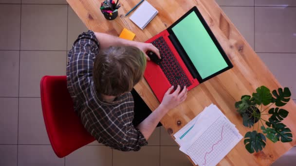Primer plano sesión superior de jóvenes caucásicos hombre de negocios de compras en línea en el ordenador portátil con pantalla verde en el escritorio en la oficina en el interior — Vídeo de stock