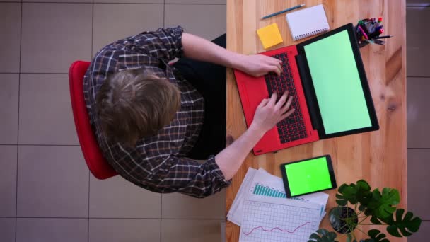 Closeup Top lő a fiatal kaukázusi üzletember gépelés a laptop a tabletta zöld képernyő az irodában beltéri — Stock videók