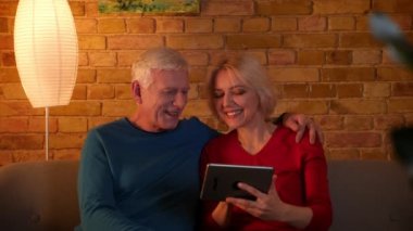 Tablette sosyal medyada sörf sörf üst düzey çift Closeup ateş mutlu rahat bir dairede kanepede oturan gülümseyerek