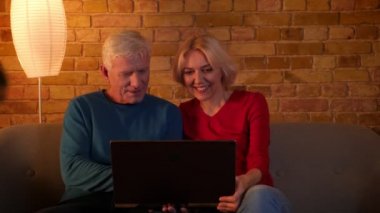 Rahat bir dairede kapalı kanepede oturan dizüstü bilgisayarda tarama üst düzey mutlu çift Closeup ateş