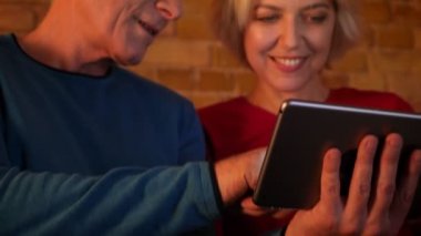 Rahat bir dairede birlikte dinlenme kanepede oturan tablet kullanarak yaşlı mutlu çift Closeup ateş