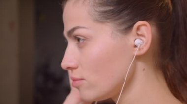 Genç çekici atlet kadın onu vibes üzerine puttting ve salonda spor salonunda motive ifade ile kameraya bakarak Closeup yan görüş çekimi