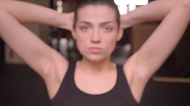 Genç fit atlet kadın ab egzersizleri yapma Closeup ateş kapalı spor salonunda kamera düz bakarak