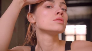 Genç çekici atlet kadın egzersiz yorgun olmak ve spor salonunda kapalı kamera bakarak sonra Closeup ateş