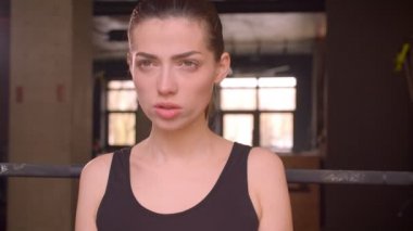 Genç çekici atlet kadın ağırlık kaldırma ve kapalı spor salonunda kamera önünde çömelme yapma Closeup ateş