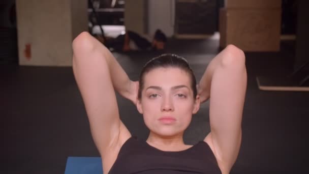 Genç çekici atlet kadın kapalı spor salonunda kamera bakarak ab egzersizleri yapma Closeup ateş — Stok video