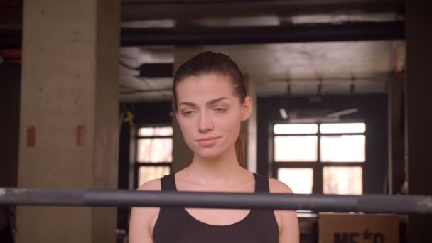 Sesión de primer plano de joven atleta atractiva mujer caminando y preparándose para levantamiento de pesas en el gimnasio en el interior — Vídeos de Stock