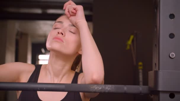 Genç çekici atlet kadın yürüyüş closeup ateş ve kapalı spor salonunda yorgunluk ile kamera bakarak ağırlık kaldırmaya hazırlanıyor — Stok video