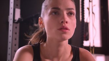 Spor salonunda oturan ve ileri ağır kapalı nefes isteyen genç çekici atlet kadın Closeup ateş