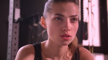 Spor salonunda oturan ve kamera ağır kapalı nefes bakarak genç aktif atlet kadın Closeup ateş