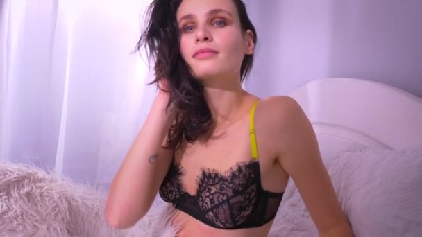 Bruneta, model v černém prádle na posteli s kožešinovou přikrývkou aktivně tančící. — Stock video