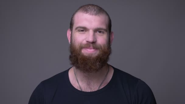 회색에 고립 된 배경으로 카메라를 행복하게 보고 행복하게 웃고있는 수염을 가진 성인 잘 생긴 근육 질 백인 남자의 클로즈업 촬영 — 비디오