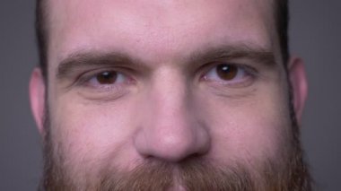 Gri izole arka plan ile gülümseyen yüz ifadesi ile kameraya bakan gözleri ile yetişkin yakışıklı kaslı kafkas erkek yüzü Closeup ateş