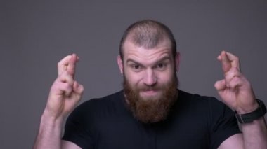 Sakallı gesturing parmakları ile yetişkin yakışıklı kaslı kafkas adam Closeup ateş gri izole arka plan ile kamera bakarak endişeli ve umutlu olmak geçti