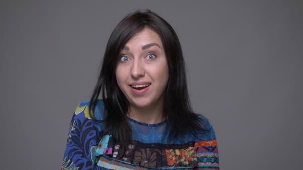 Close-up portret van volwassen Kaukasische brunette vrouw wordt opgewonden en glimlachend kijken naar camera met achtergrond geïsoleerd op grijs — Stockvideo