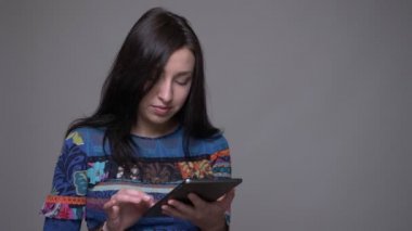 Tablet kullanarak yetişkin kafkas esmer kadın Closeup portre ve gri izole arka plan ile kamera bakıyor