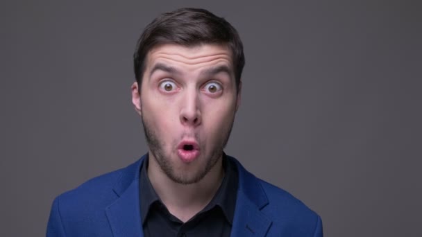 Closeup shoot of young handsome caucasian man being excited and smiling looking at camera with background isolated on gray — Stock Video