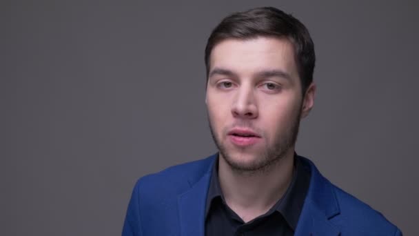 Closeup shoot of young handsome caucasian man smiling happily looking at camera with background isolated on gray — Stock Video