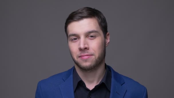 Closeup shoot of young handsome caucasian man laughing cheerfully looking at camera with background isolated on gray — Stock Video