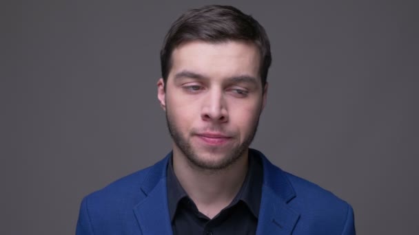 Šnečivý zastřelí mladého pohledného kavkazského muže, který je smutný a zklamaný, když se díval na kameru s pozadím izolovaným na šedé — Stock video