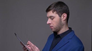 Gri üzerinde izole arka plan ile kamera önünde tablet kullanarak genç yakışıklı beyaz adam Closeup çekim