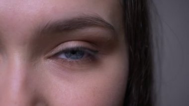Mavi pırıl pırıl göz kırpma ve kamera bakarak genç çekici kadın yüz Closeup yarım yüz çekimi