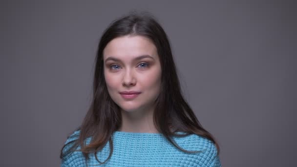 Närbild shoot av ung Söt brunett kvinnlig leende förföriskt tittar på kamera med bakgrund isolerad på grå — Stockvideo