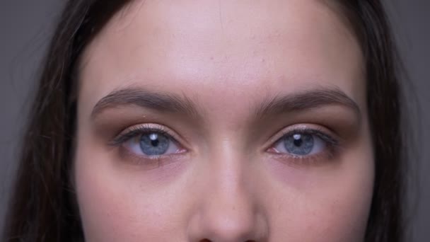 Close-up shoot van jonge aantrekkelijke vrouwelijke gezicht met blauwe sprankelende ogen kijken naar camera — Stockvideo