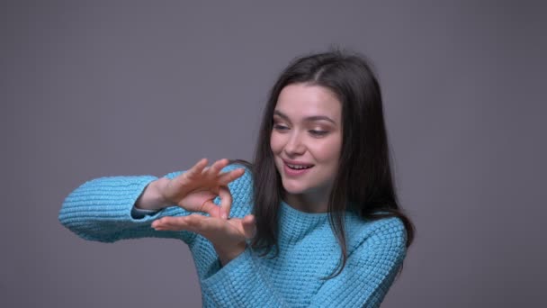 Gros plan tige de jeune jolie brune femelle mime geste et imaginaire papillon avec fond isolé sur gris — Video