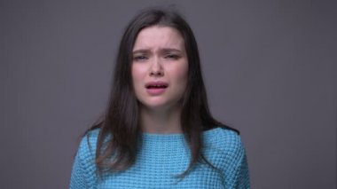 Genç güzel esmer kadın yakın çekim iğrenmiş ve gri izole arka plan ile kameraya bakarak rahatsız