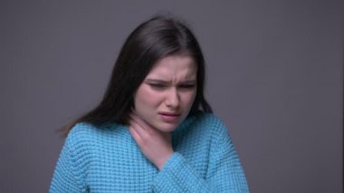 Genç güzel esmer kadın bir hasta boğaz gri izole arka plan ile kamera önünde hasta olan closeup ateş