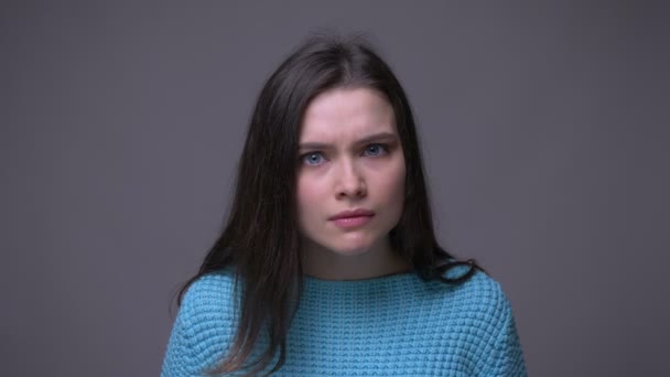 Närbild shoot av unga ganska brunett kvinna är arg och rasande tittar på kamera med bakgrund isolerade på grått — Stockvideo
