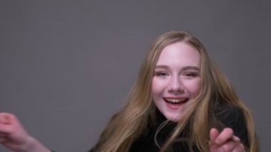 Genç çekici esmer kadın saçları çırpınan etrafında dönüyor ve mutlu gri izole arka plan ile kameraya bakarak gülümseyen Closeup portre