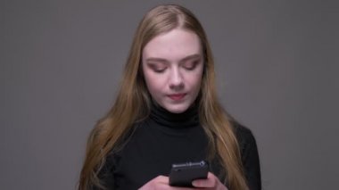 Telefonu kullanarak ve gri izole arka plan ile mutlu gülümseyen genç çekici esmer kadın Closeup portre