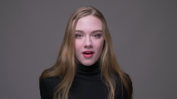 Close-up retrato de jovem atraente morena fêmea ficando animado e surpreso na frente da câmera com fundo isolado em cinza — Vídeo de Stock