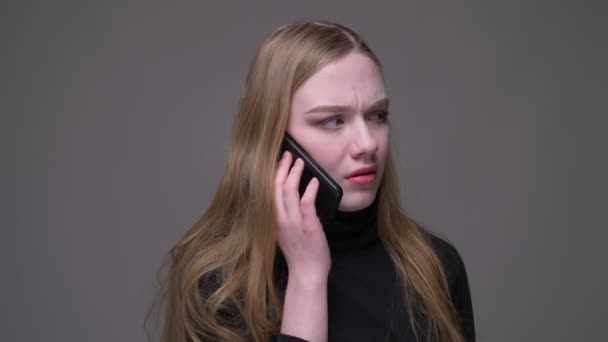 Close-up portret van jonge aantrekkelijke brunette vrouw met een telefoontje praten emotioneel met achtergrond geïsoleerd op grijs — Stockvideo