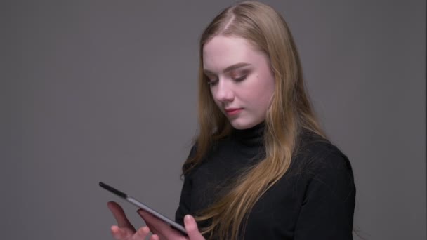 Gros plan portrait de jeune belle brune femelle à l'aide de la tablette et montrant écran chromatique vert à la caméra avec fond isolé sur gris — Video