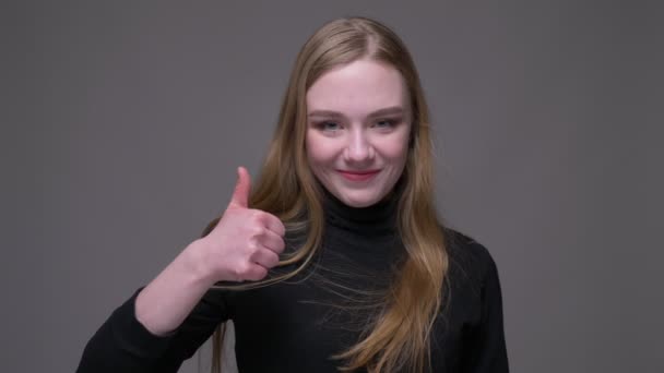 Nahaufnahme Porträt der jungen attraktiven brünetten Frau zeigt einen Schlag nach oben Blick auf die Kamera mit Hintergrund isoliert auf grau — Stockvideo