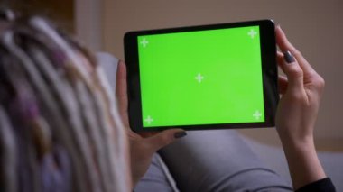 Rahat bir dairede kanepede yatan yeşil renk anahtar ekranı ile tablet kullanarak dreadlocks ile genç kafkas hipster kadın Closeup geri görüş çekimi